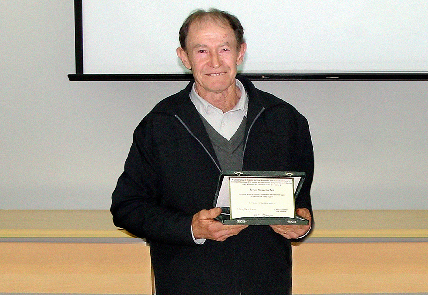  Zenuir Zatt segurando placa de homenagem pelos 20 anos de Conselho 