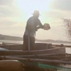  Homem em pé dentro de uma canoa alimentando peixes 