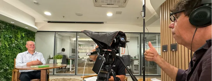  O presidente está sentado frente a uma câmera. 