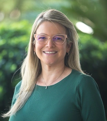  Mulher loira, de óculos de grau, com a camiseta verde, sorrindo 