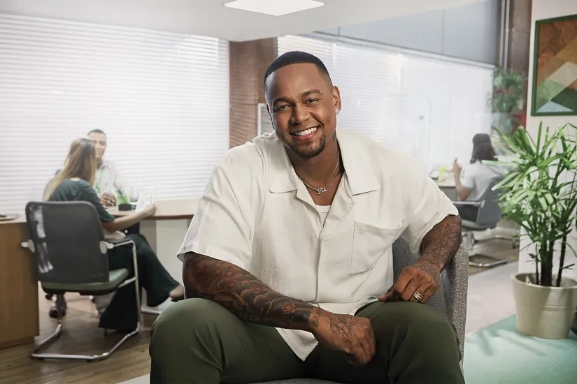  Leo Santana sentado com camisa branca e calça jeans. 