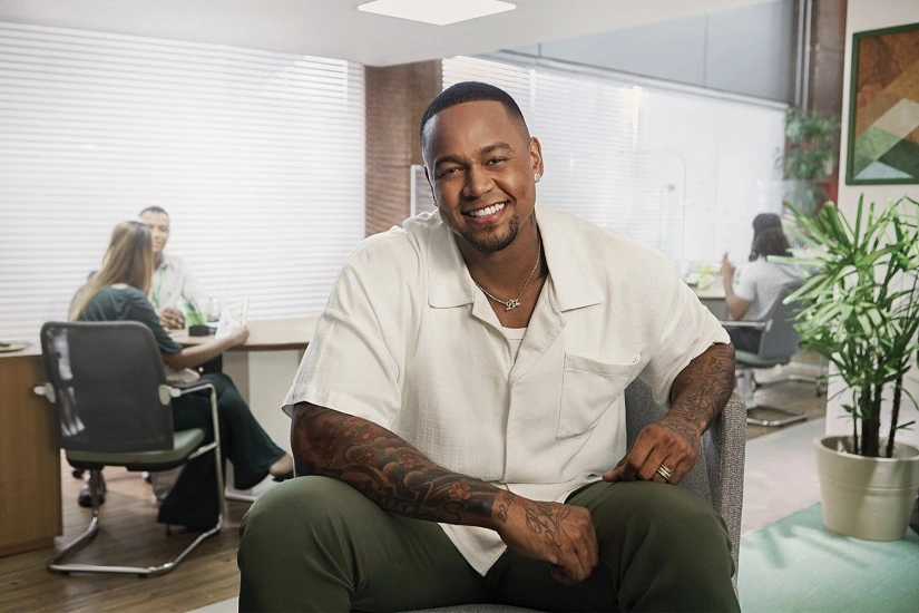  Leo Santana sentado com camisa branca e calça jeans. 