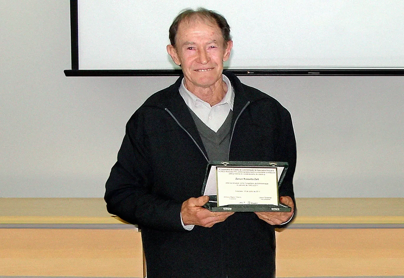  Zenuir Zatt segurando placa de homenagem pelos 20 anos de Conselho 