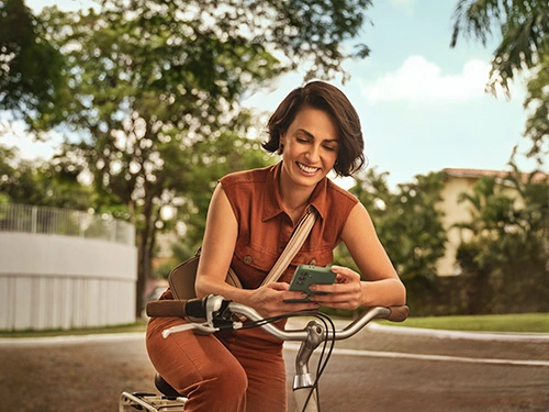  Mulher mexendo em seu celular montada em uma bicicleta 