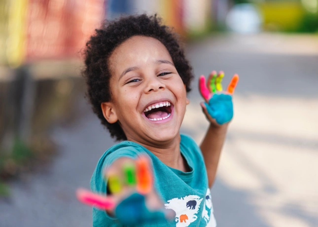 Criança feliz com as mãos sujas de tinta