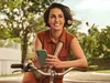 Mulher em uma bicicleta, parada, sorrindo para o horizonte. 