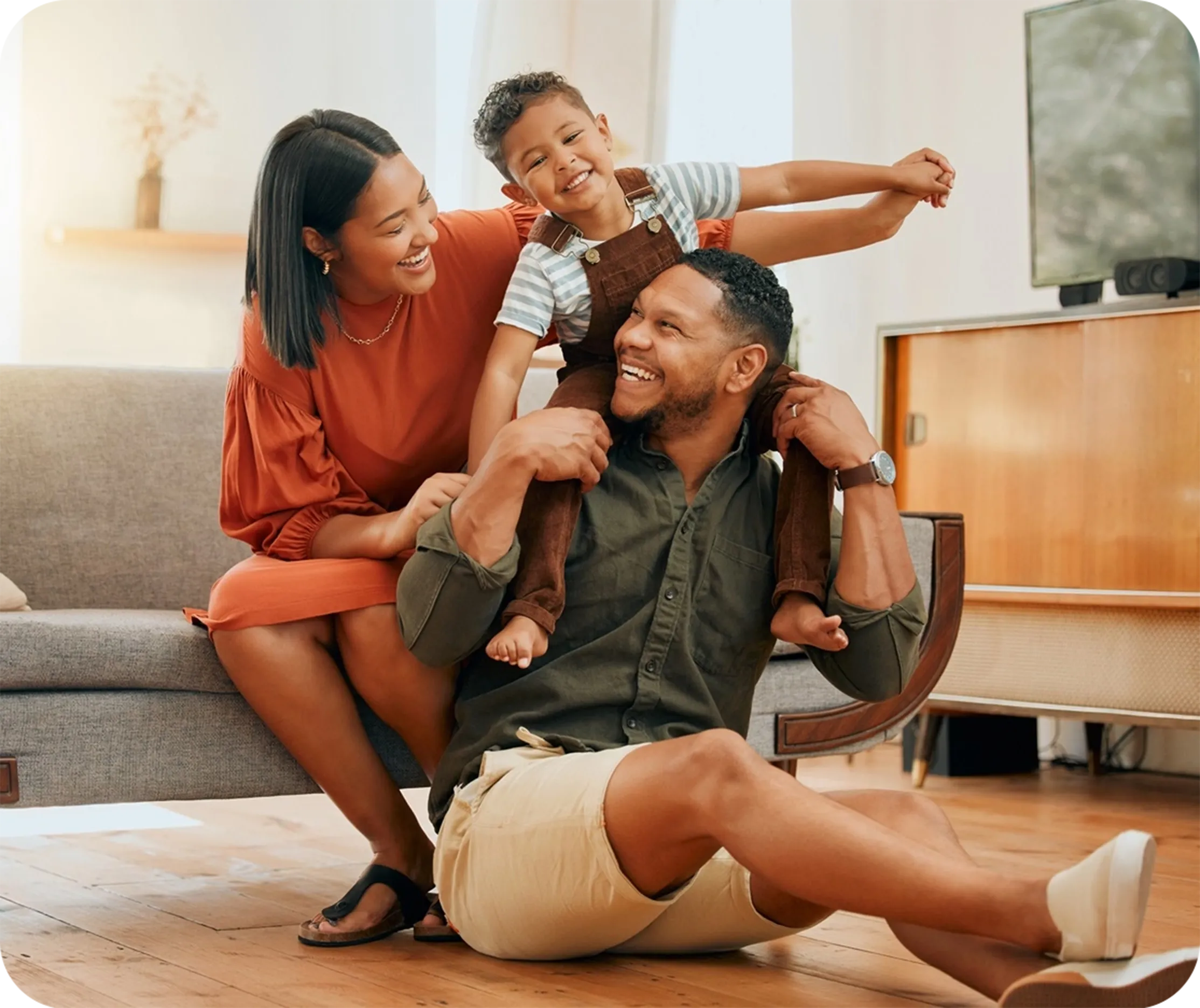 Família feliz com filho, sentados em um sofá e dando risada.