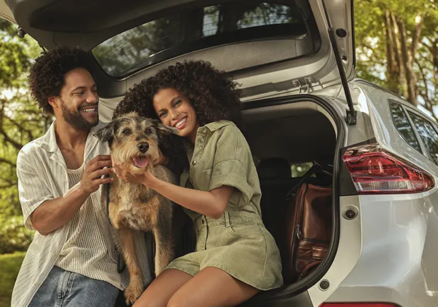  familia com homem mulher e cachorro sentados no portal malas do carro 