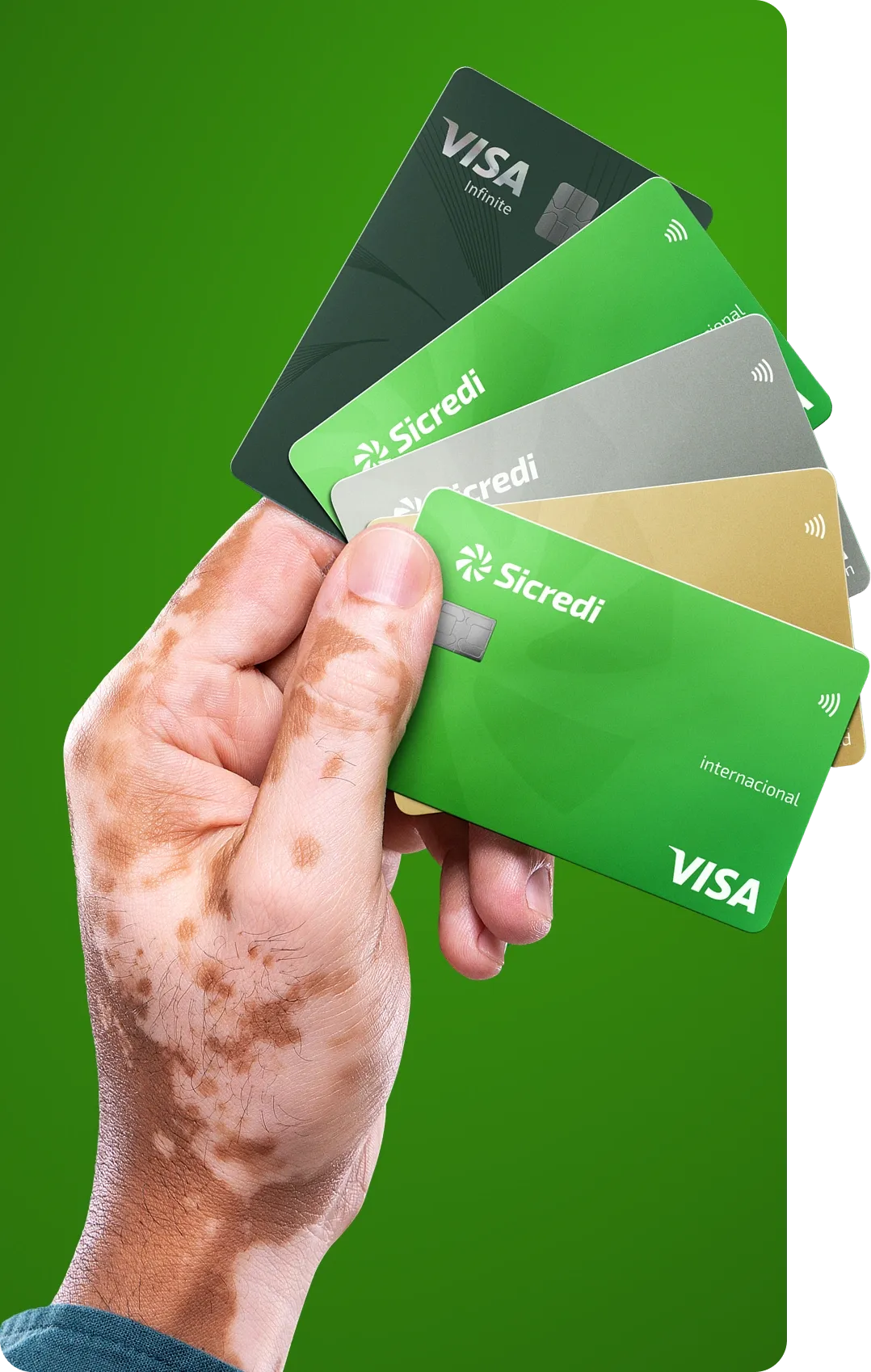  Mão segurando cinco cartões Sicredi da bandeira Visa, dispostos em leque, com diferentes cores e categorias, sobre fundo verde. 