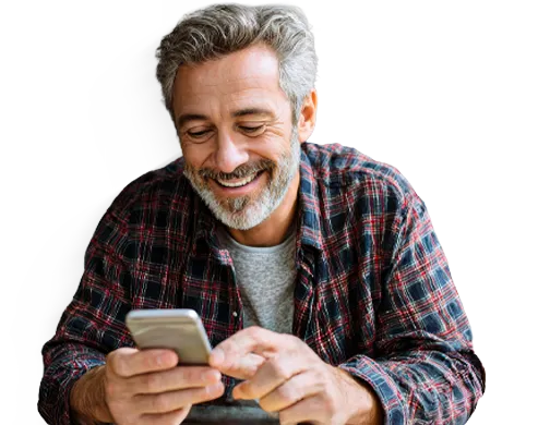  Pessoa sentada segurando um smartphone, usando camisa xadrez e camiseta cinza, olhando para o aparelho. 