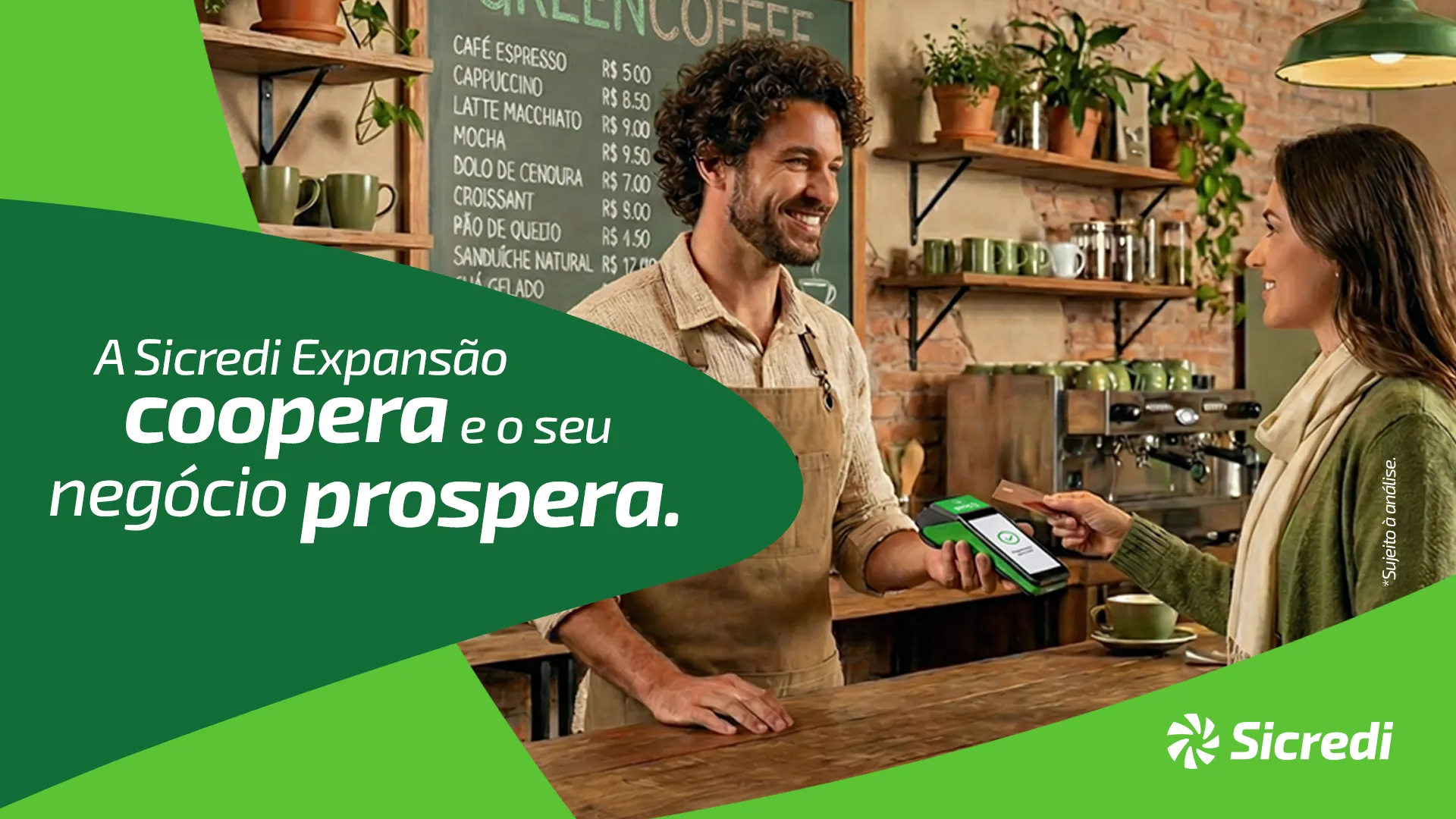  Homem de pele clara sorrindo olhando pra uma pessoa, segurando uma maquininha 