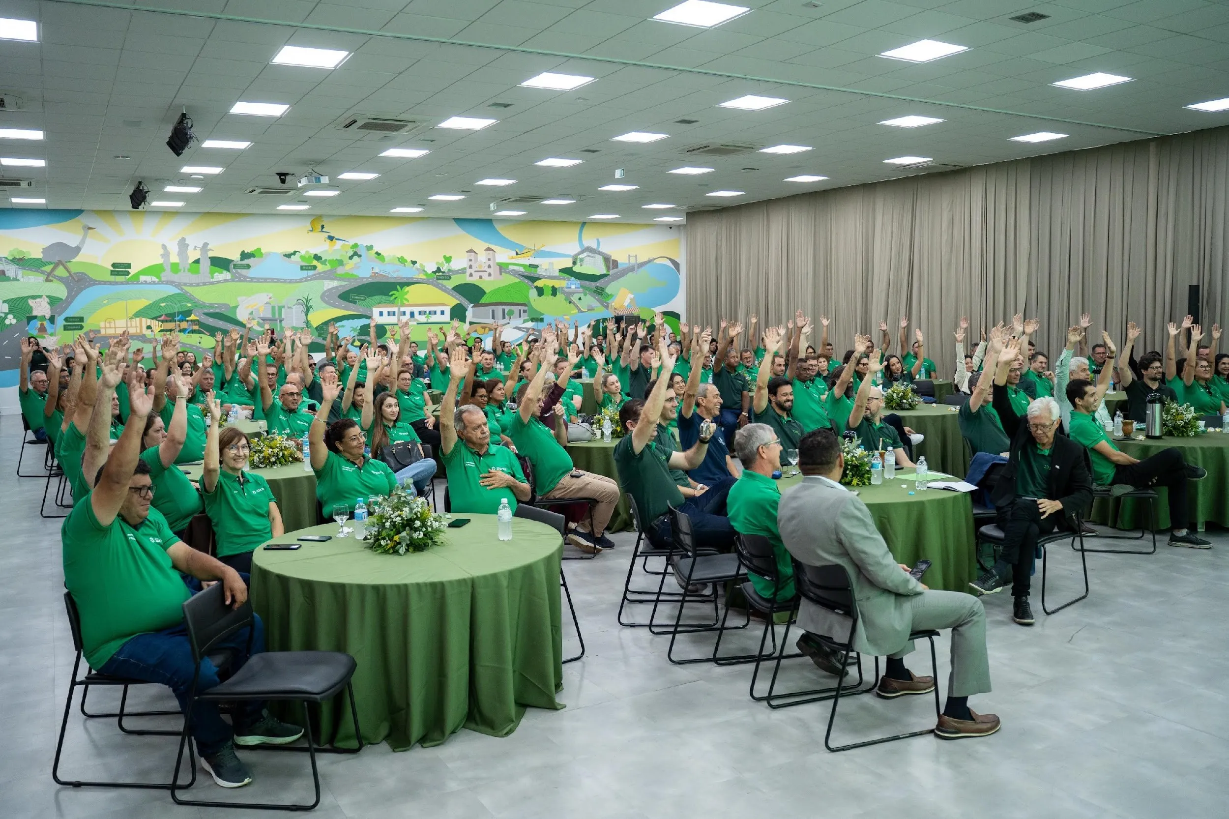  Pessoas reunidas votando em uma assembleia extraordinária do Sicredi 