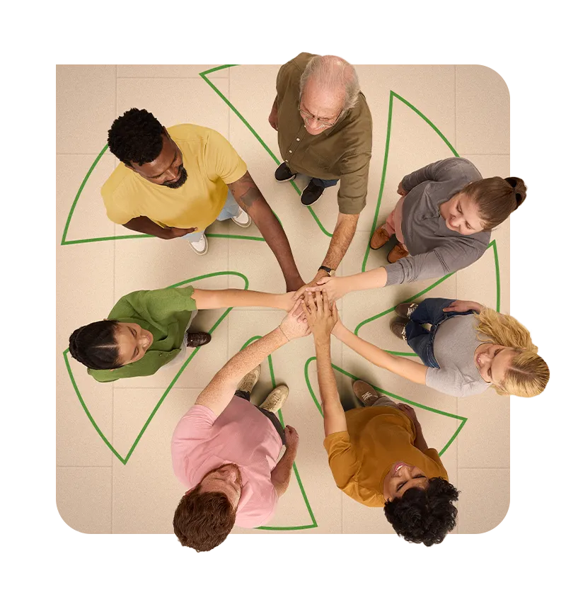  Vista superior de um grupo de pessoas em círculo, com as mãos unidas ao centro, sobre o piso com o símbolo do Sicredi em verde, representando cooperação e união. 