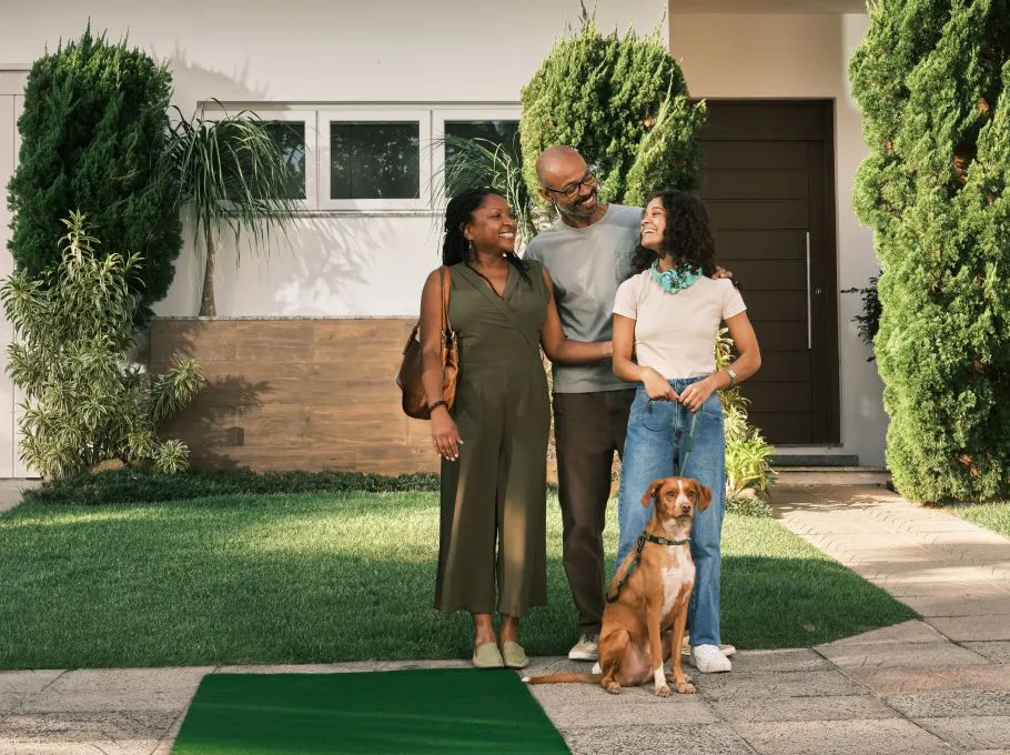  Casal com filha e cachorro no que parece ser uma nova casa, adquirida com o consórcio do Sicredi. 