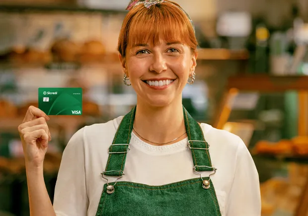  Mulher segurando o cartão Sicredi Empresarial. 