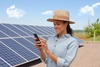  mulher usando o celular na frente de placas solares 