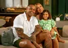  Leo Santana, Lore Improta e filha sorriem em sofá em casa 