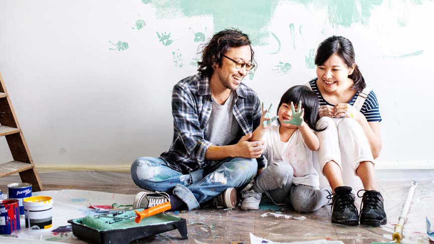 Família sentada no chão suja de tinta após a pintura