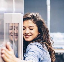 Mulher feliz abraçada na geladeira em uma loja de eletrônicos