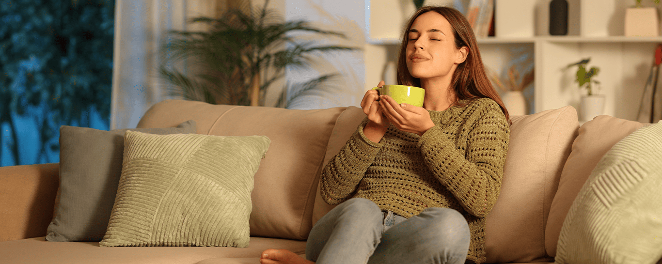  mulher sentada no sofá com uma caneca na mão 
