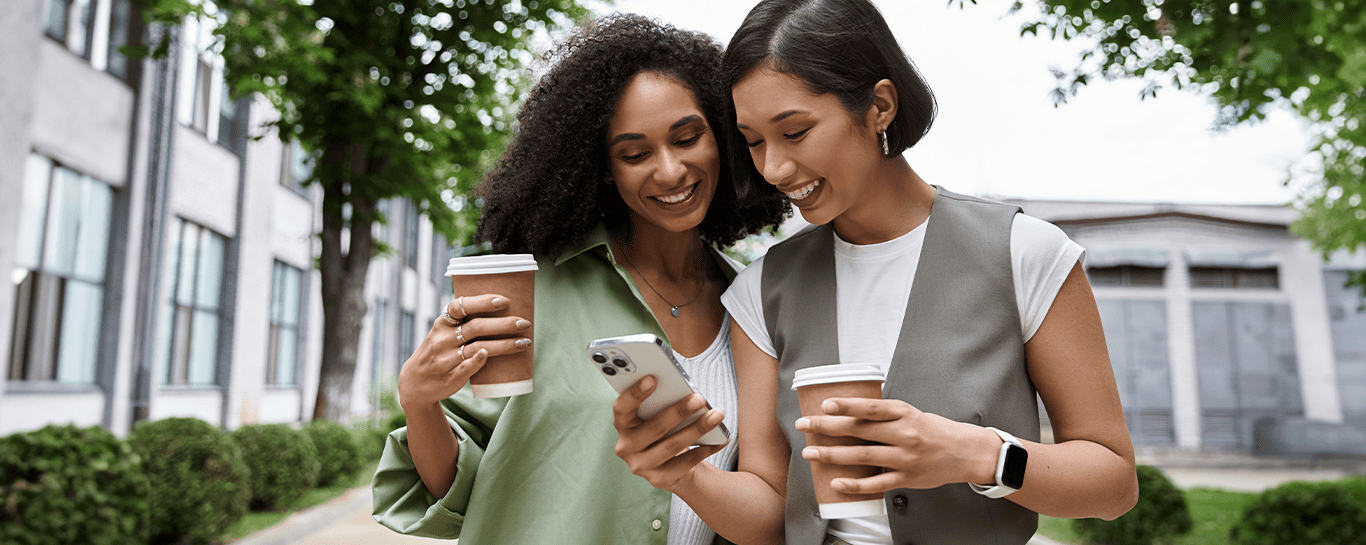  mulher com copo na mão e outra com celular na mão 