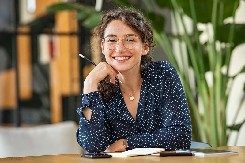  mulher de óculos com lápis na mão sorrindo 