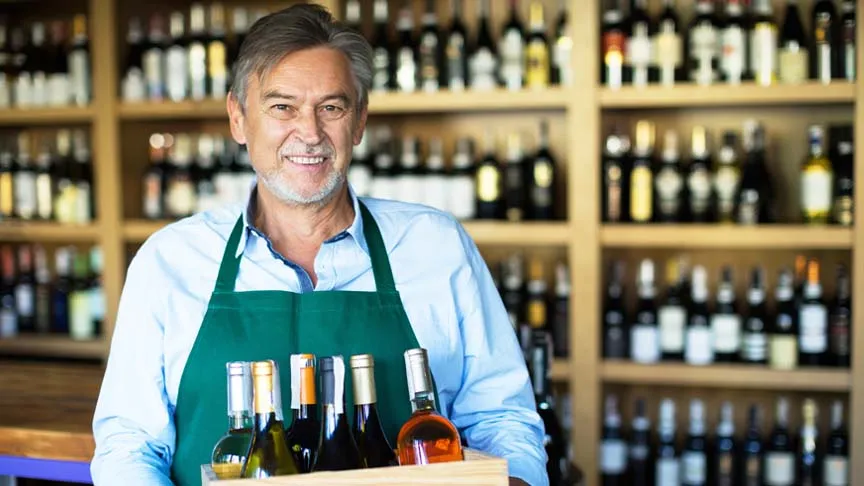  Vendedor de vinhos importados segurando uma caixa em sua loja 