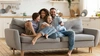  Pai, mãe, filho e filha sentados no sofá, se abraçando e rindo 