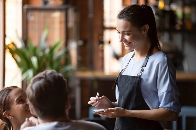  Mulher atendendo cliente em um restaurante com seguro para empresa Sicredi 