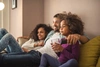  pai, mãe e filha sentados no sofá de casa com a cobertura do seguro sicredi 