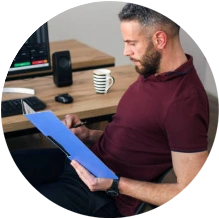  Homem sentado em cadeira fazendo anotações em uma planilha 