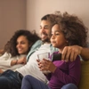  pai, mãe e filha sentados no sofá de casa com a cobertura do seguro sicredi 