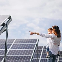  Mulher segurando bebê e apontando para placas solares. 