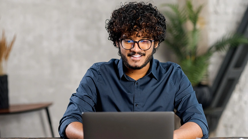  Homem sentado em frente ao desktop realizando pagamentos através da solução boletos, contas e tributos Sicredi. 