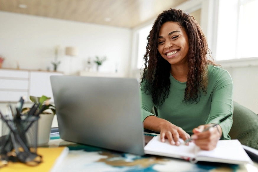  Mulher sorrindo e conferindo os conteúdos do Explica aí, Sicredi pelo computador 