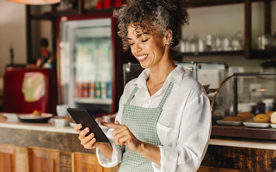 mulher empreendedora vestindo camisa branca e avental cinza, usando o aplicativo da máquina de cartões smart do sicredi