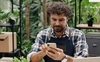  homem empreendedor vestindo camisa xadrez e avental azul, usando o portal online da máquina de cartões smart do sicredi 