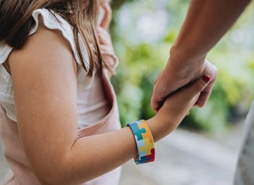 criança com autismo de mãos dadas com responsável