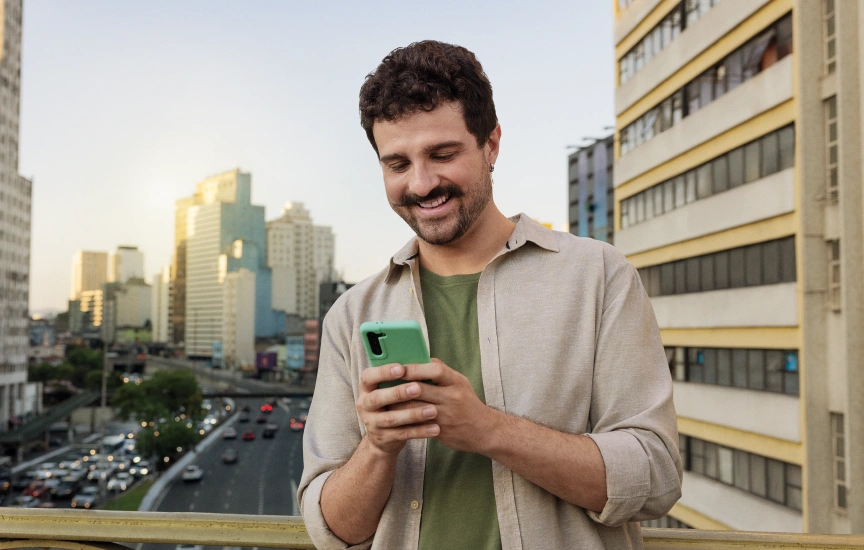  Associado do Sicredi utilizando seu celular e sorrindo 