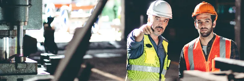 dois homens brancos com EPI trabalham em obra