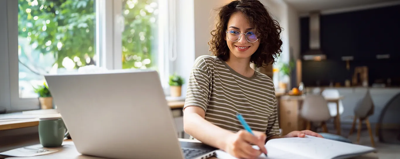 mulher branca em frente a notebook fazendo planejamento financeiro
