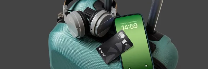fone de ouvido preto ao lado de celular e cartão Sicredi Mastercard Black