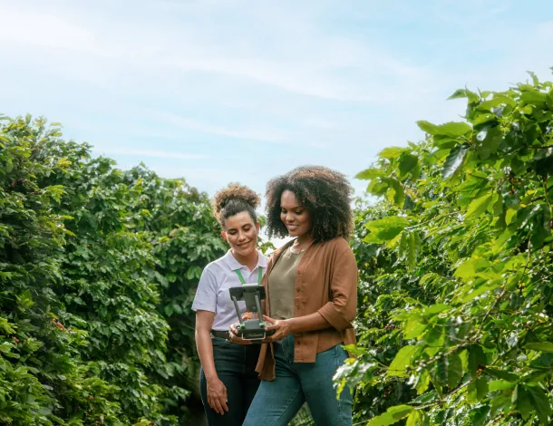 duas mulheres operam drone sobre plantação