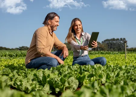 homem negro com chapéu no campo sorri olhando para celular