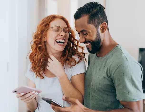  homem e mulher sorriem com celular na mão 