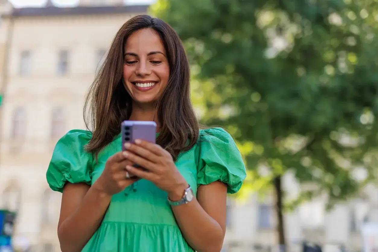  Mulher jovem usando celular e sorrindo 