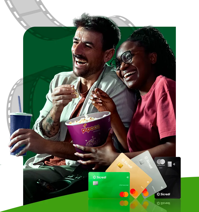  Banner promocional da Sicredi com benefício de cinema. Em destaque, duas pessoas sentadas compartilhando um balde de pipoca e um refrigerante. Na parte inferior da imagem, aparecem cartões Sicredi Mastercard de diferentes categorias. 