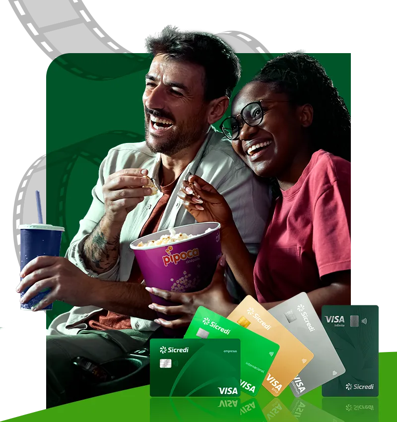  Banner promocional da Sicredi com benefício de cinema. Em destaque, duas pessoas sentadas compartilhando um balde de pipoca e um refrigerante. Na parte inferior da imagem, aparecem cartões Sicredi Visa de diferentes categorias. 